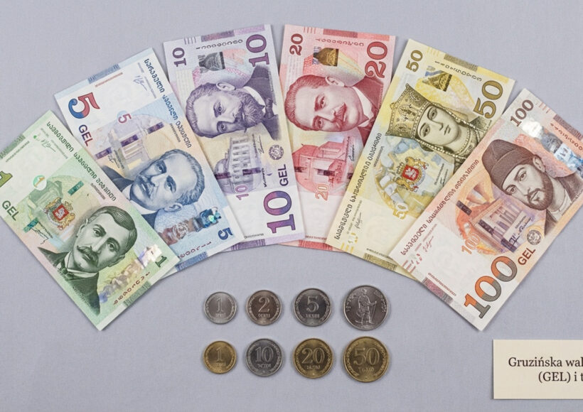 Przejrzysta fotografia banknotów i monet gruzińskiej waluty na neutralnym tle, ukazująca szczegóły i symbole narodowe.
