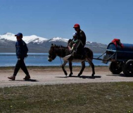 Mieszkańcy Kirgistanu z końmi i wózkiem nad górskim jeziorem podczas podróży Nomads
